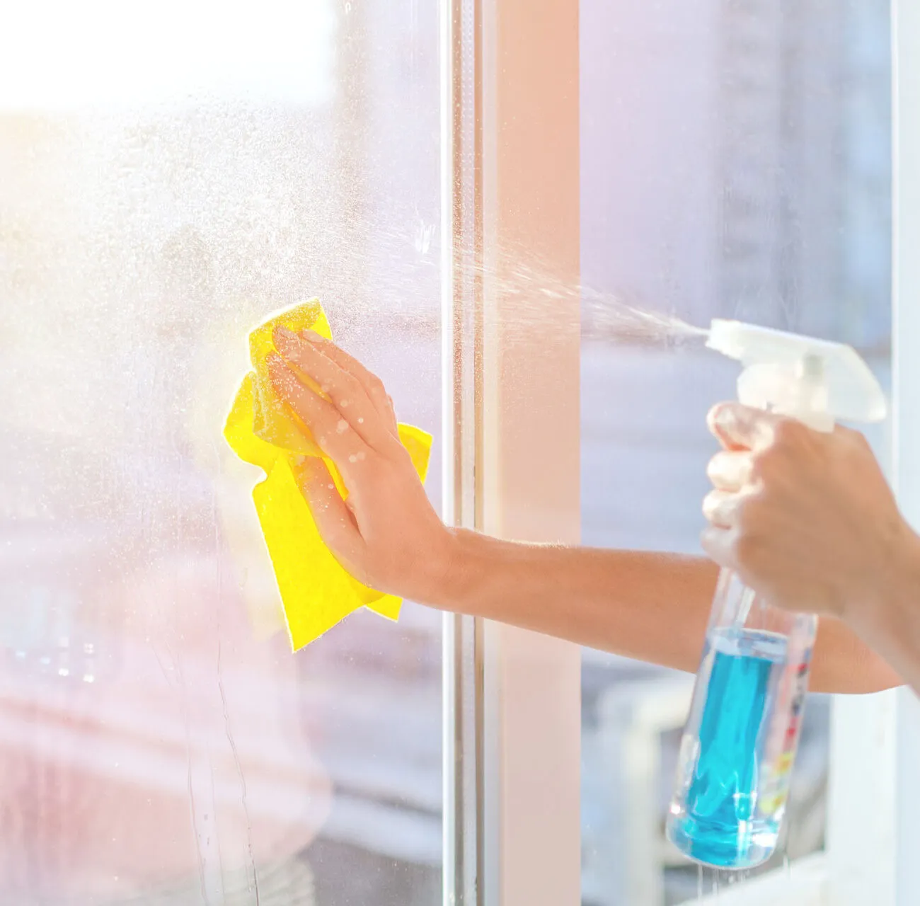 Window-cleaning-1136340520 Hands with napkin cleaning window. Washing the glass on the windows with cleaning spray. Selective soft focus. Empty place for text, copy space. Window cleaning home.